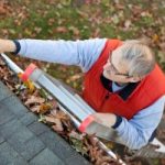 Man on ladder cleaning gutter