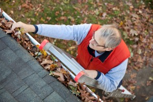 Man on ladder cleaning gutter