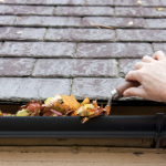 Man scooping leaves out of gutter