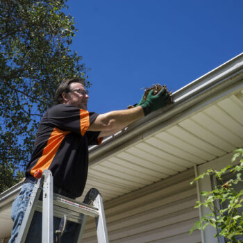 Worker cleaning gutters on a customers home.