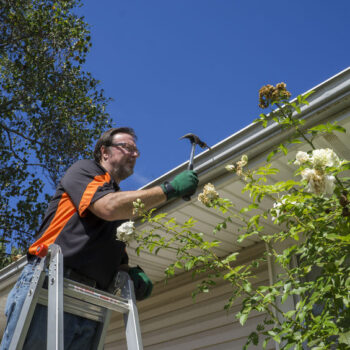 Worker hammering gutter spike in that came loose.