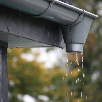 a closeup shot of water drops falling from rain gutters